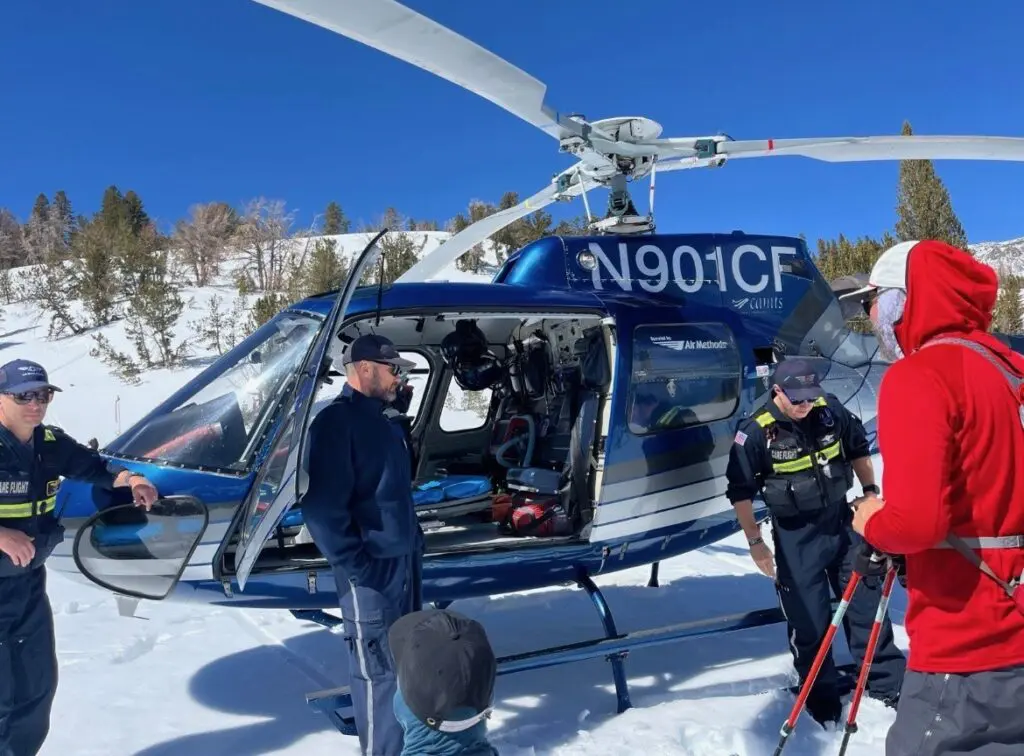 People stand next to a helicopter in the snow.