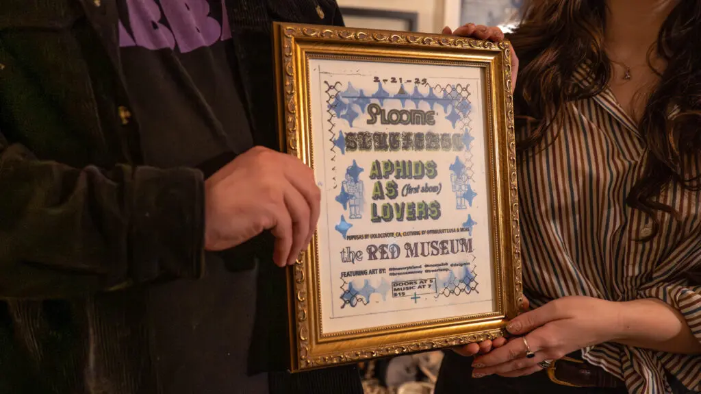 people hold framed flyer from their first art and music event collaboration at Red Museum.
