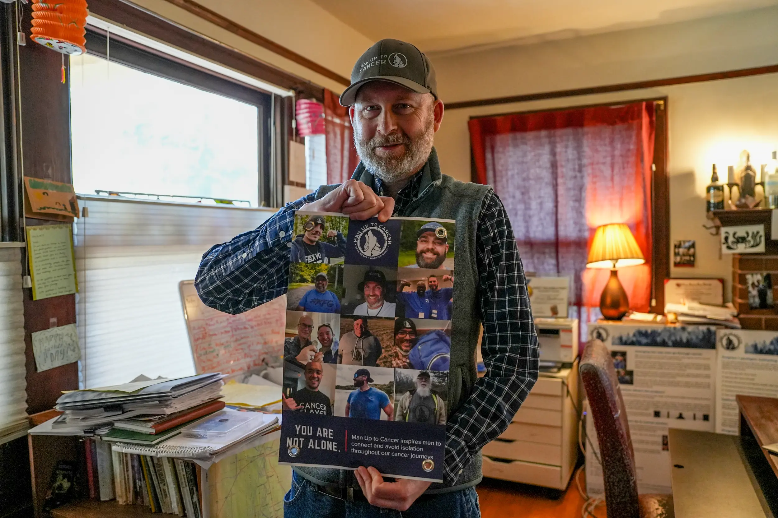 Brad Buchanan, NorCal chapter leader of Man Up to Cancer, holds a sign from the organization in his home. Photo by Denis Akbari.