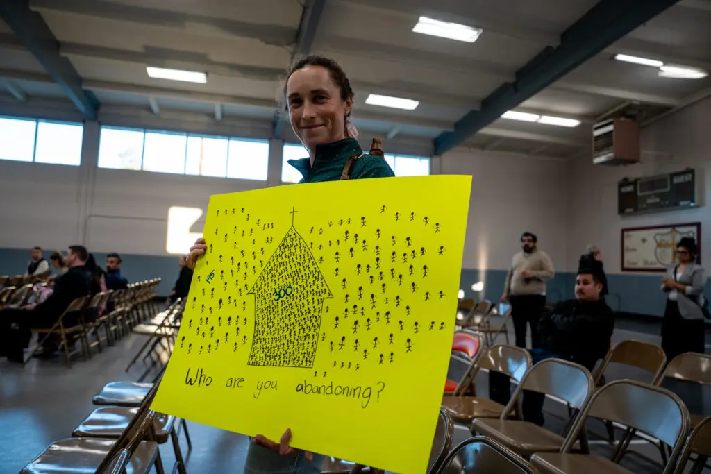 Hope Janelle Jones, St. Patrick Academy parent, holding a sign at the merger meeting at St. Robert Catholic School on Feb. 12, 2026. Photo by Denis Akbari.