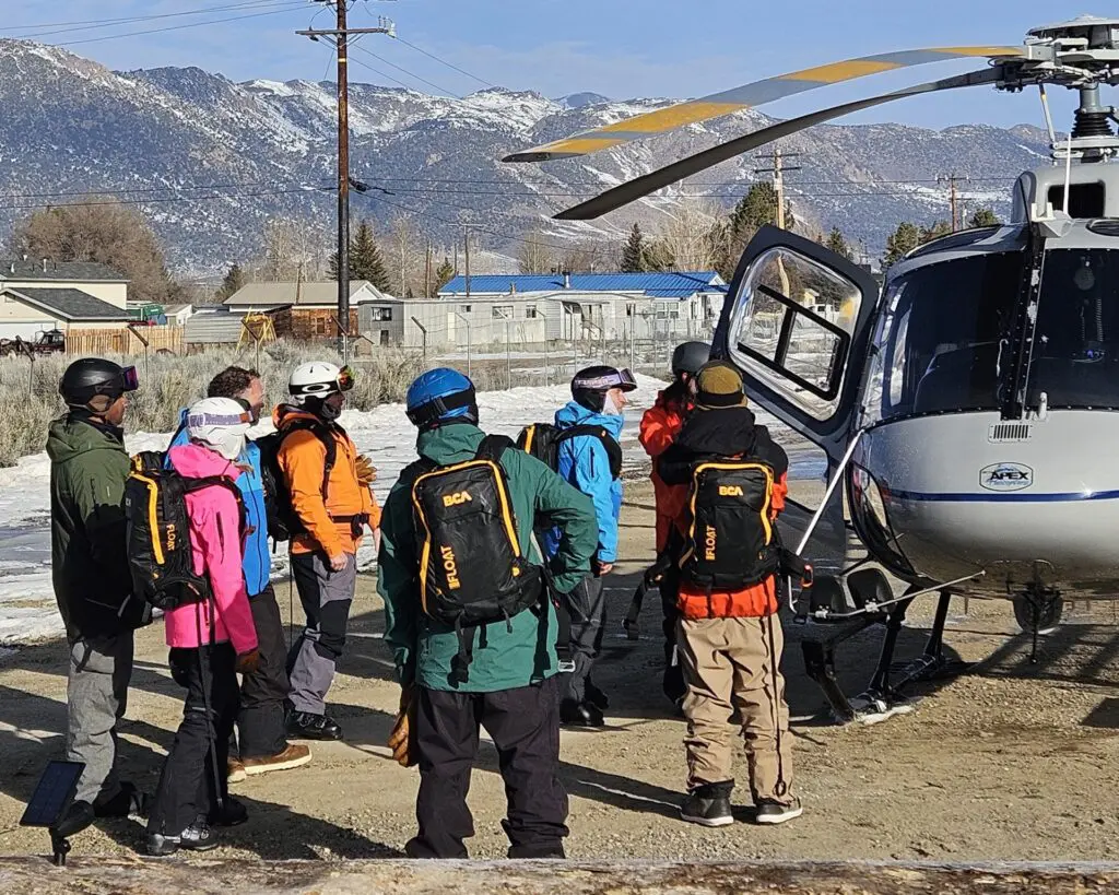 People stand next to a helicopter