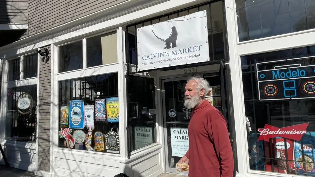 Man standing outside market holding a sandwich