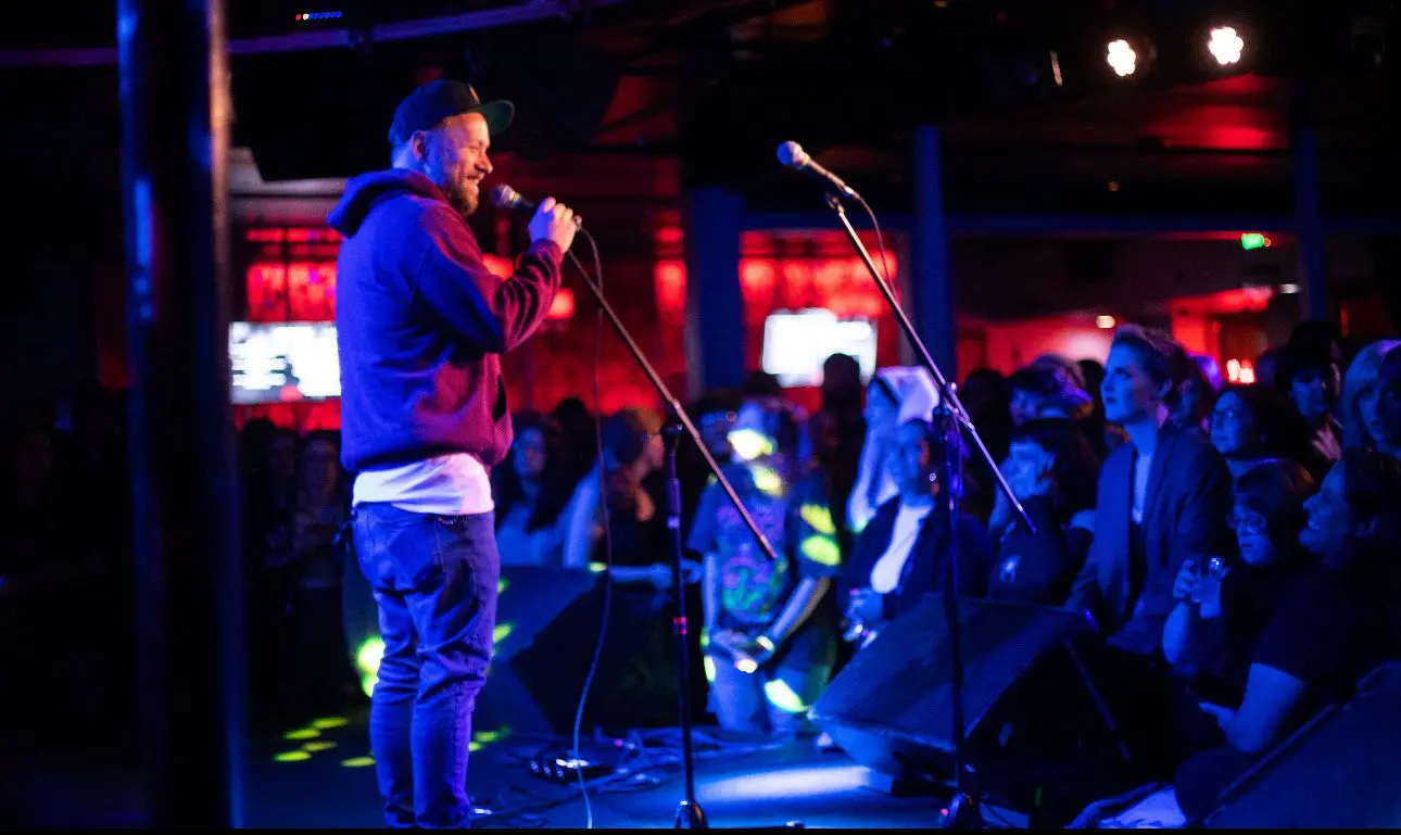 A man on a stage reads poetry