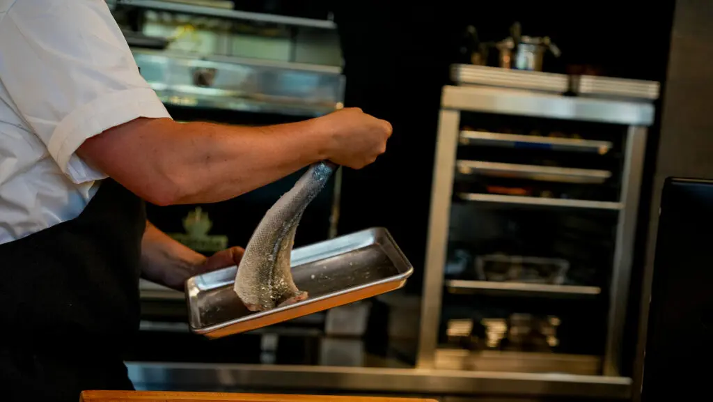 Chef making Wood Roasted Branzino dish at Aiona. Photo by Denis Akbari.