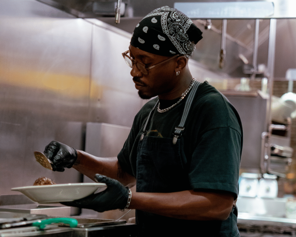 Chef standing in kitchen holding spoon, preparing food
