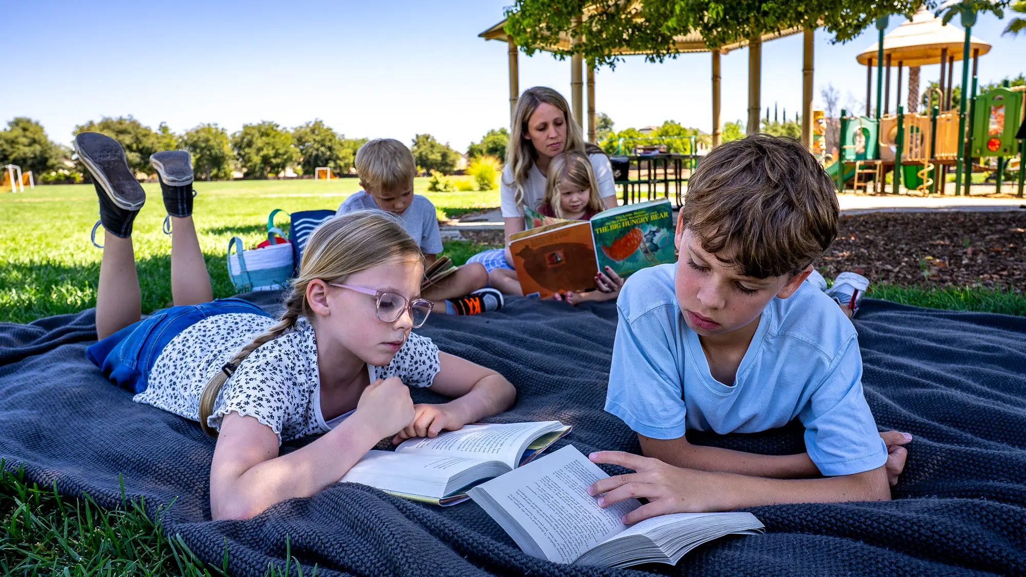 kids and their mom reading in a park