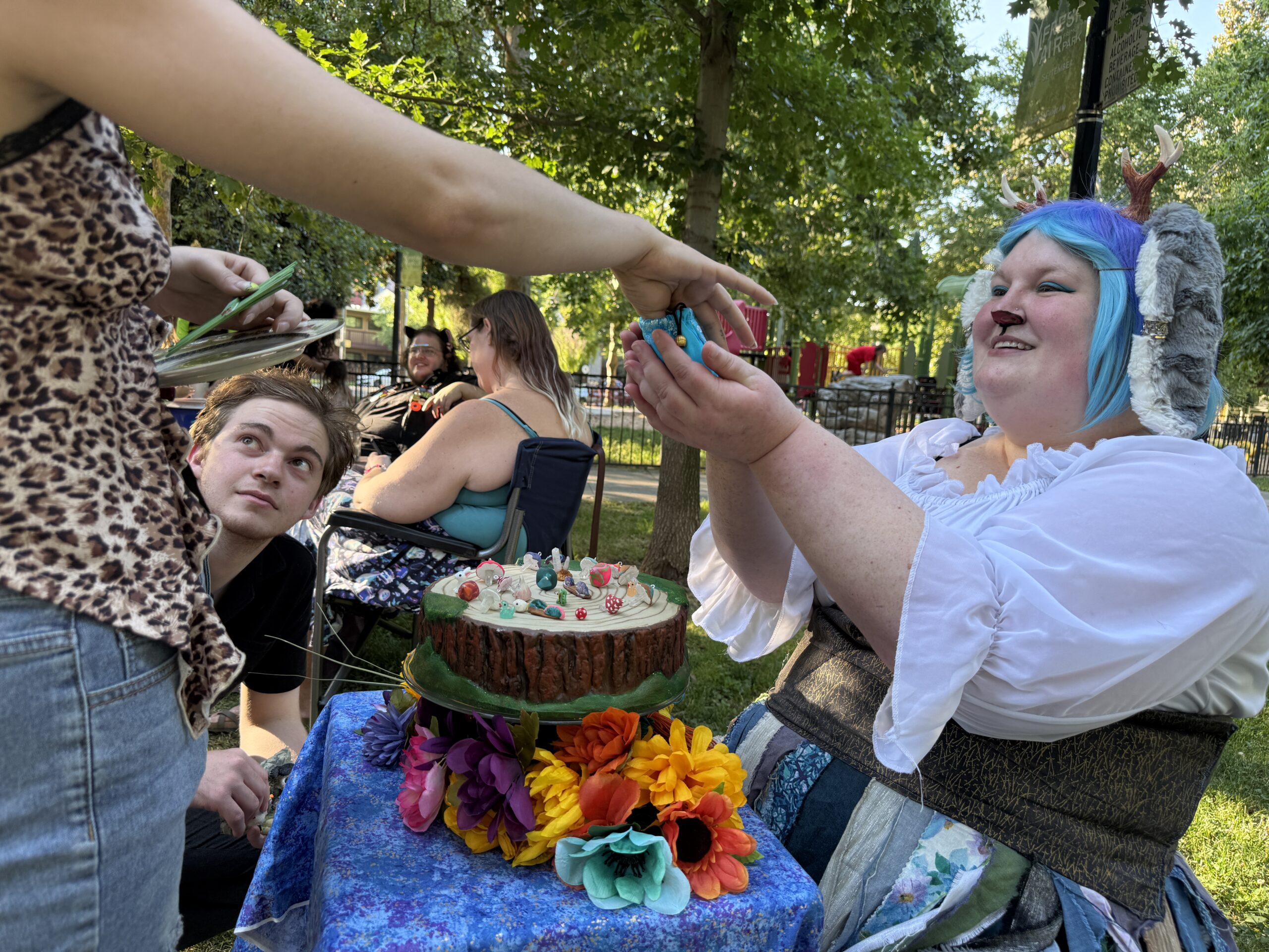 Woman in white shirt and blue hair trades a small art piece.