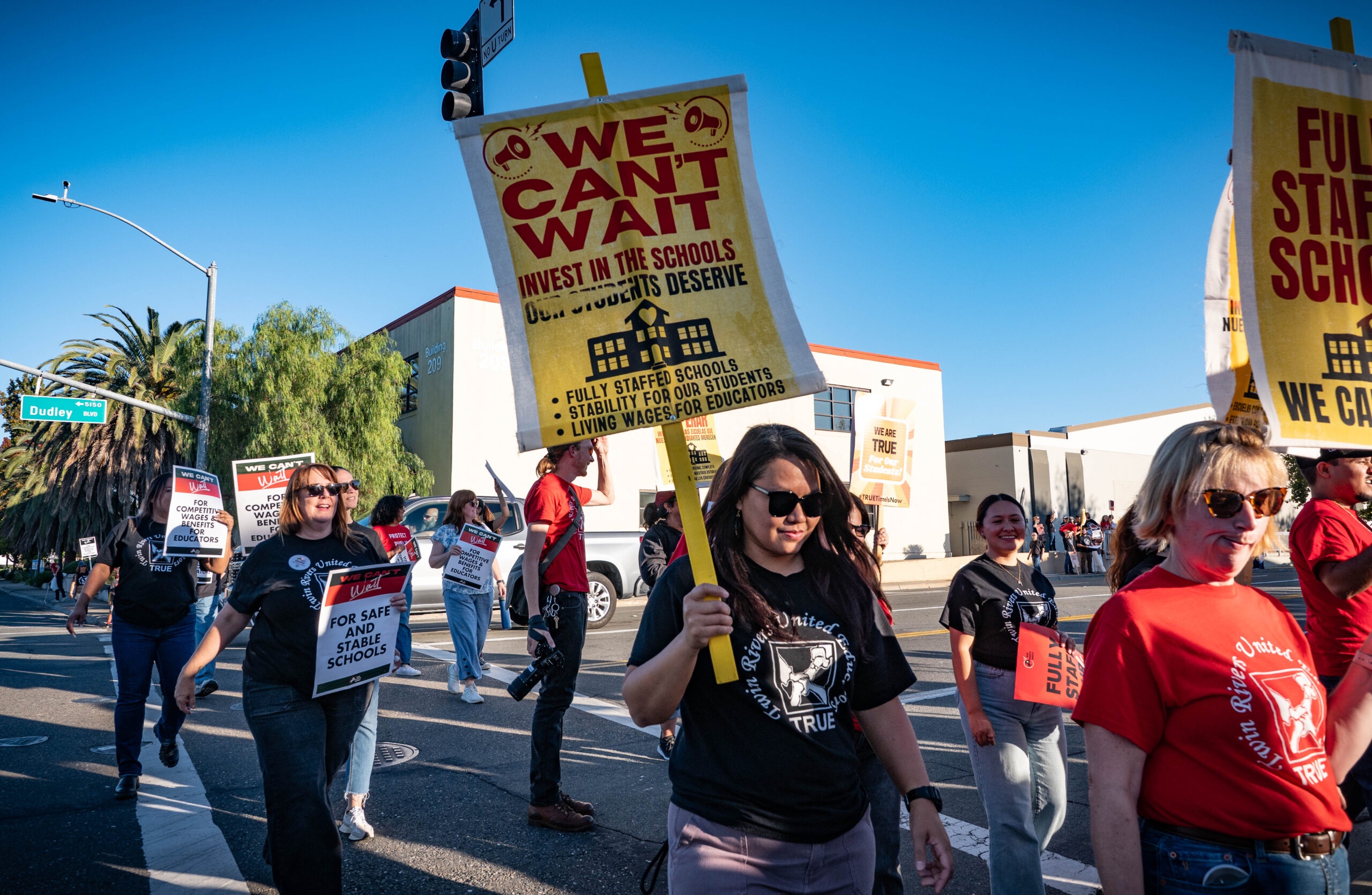 Teachers, parents, and community members cross the street to join the rally in front of Twin Rivers Unified School District on Tuesday, Oct. 21, 2025.