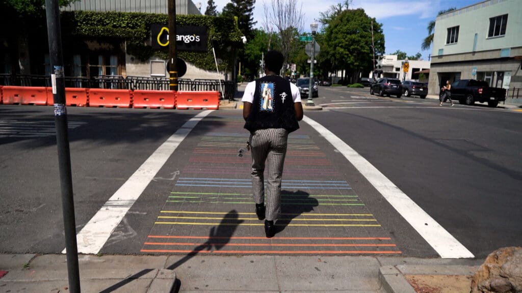man walking across rainbow sidewalk
