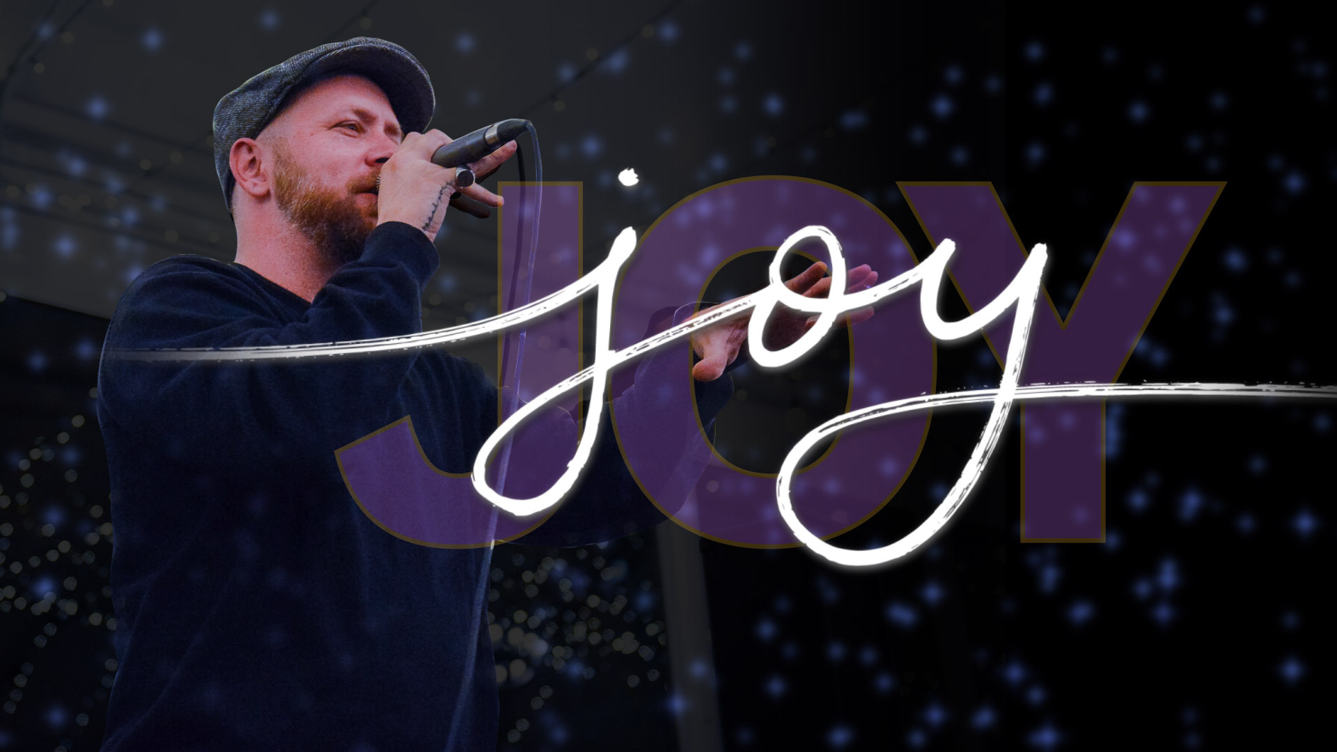 Poet speaks into microphone with stylized wording for the term "joy" beside him
