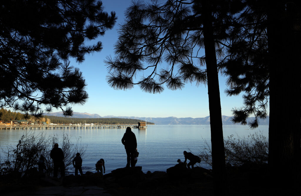 People stand on the shores of Lake Tahoe in Tahoe City
