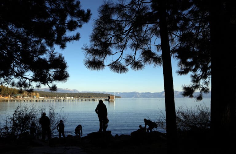People stand on the shores of Lake Tahoe in Tahoe City