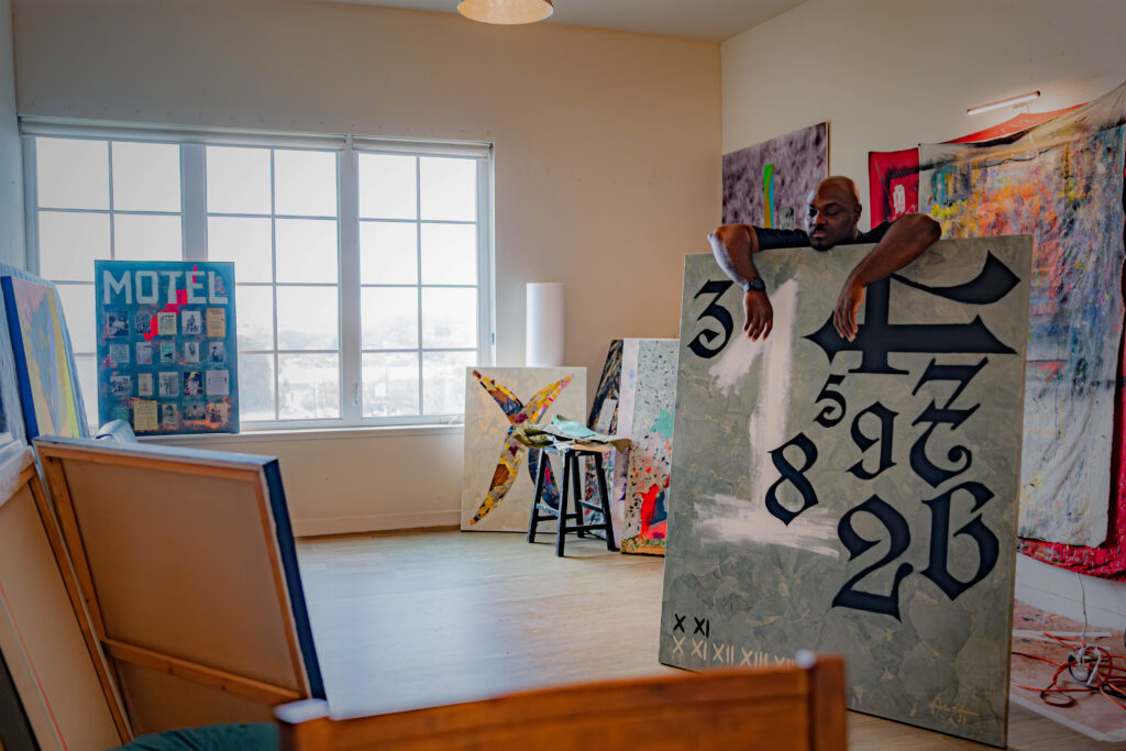 man stands over large painting