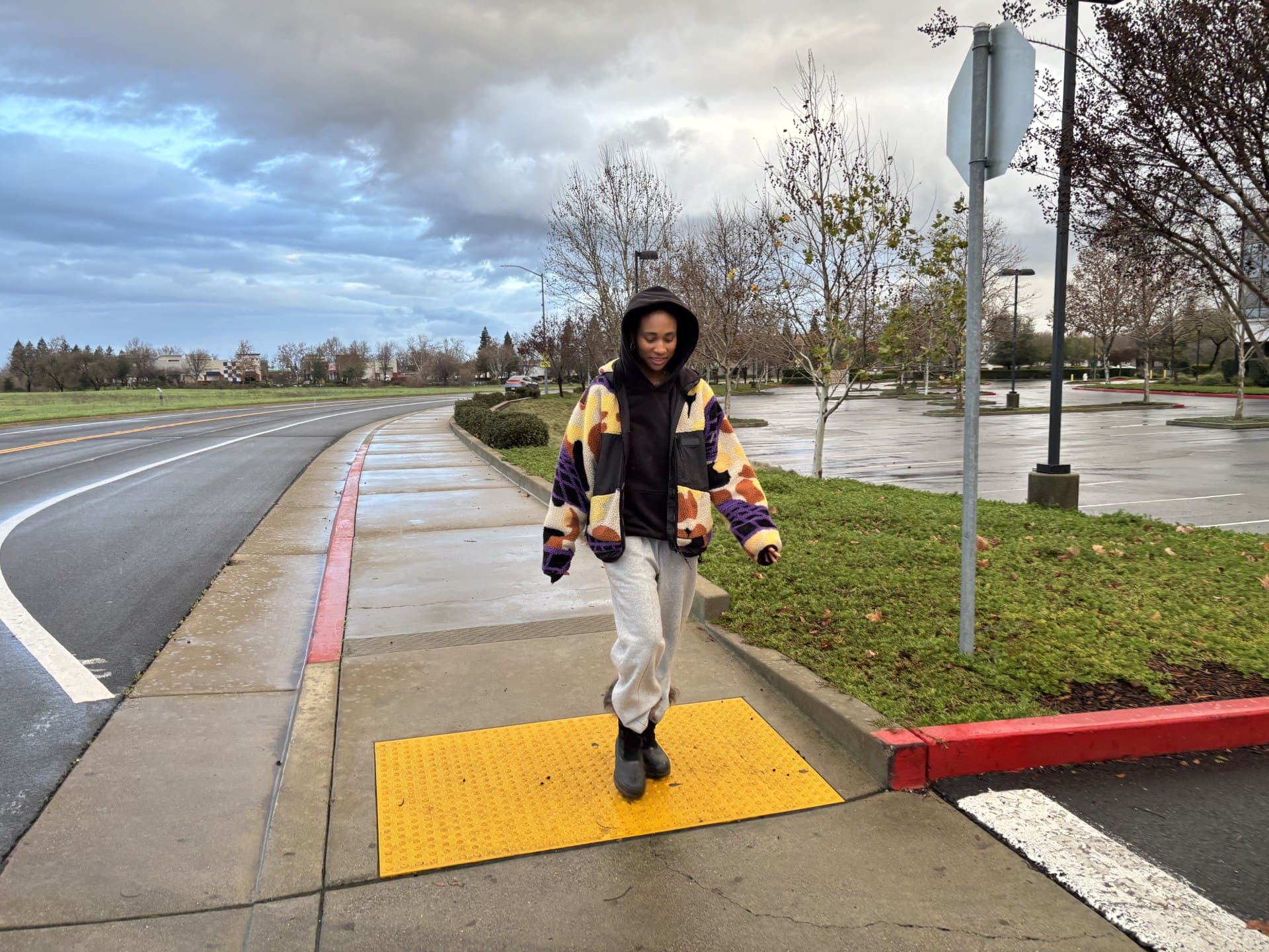 Woman walks outside on cloudy day with her hood over her head