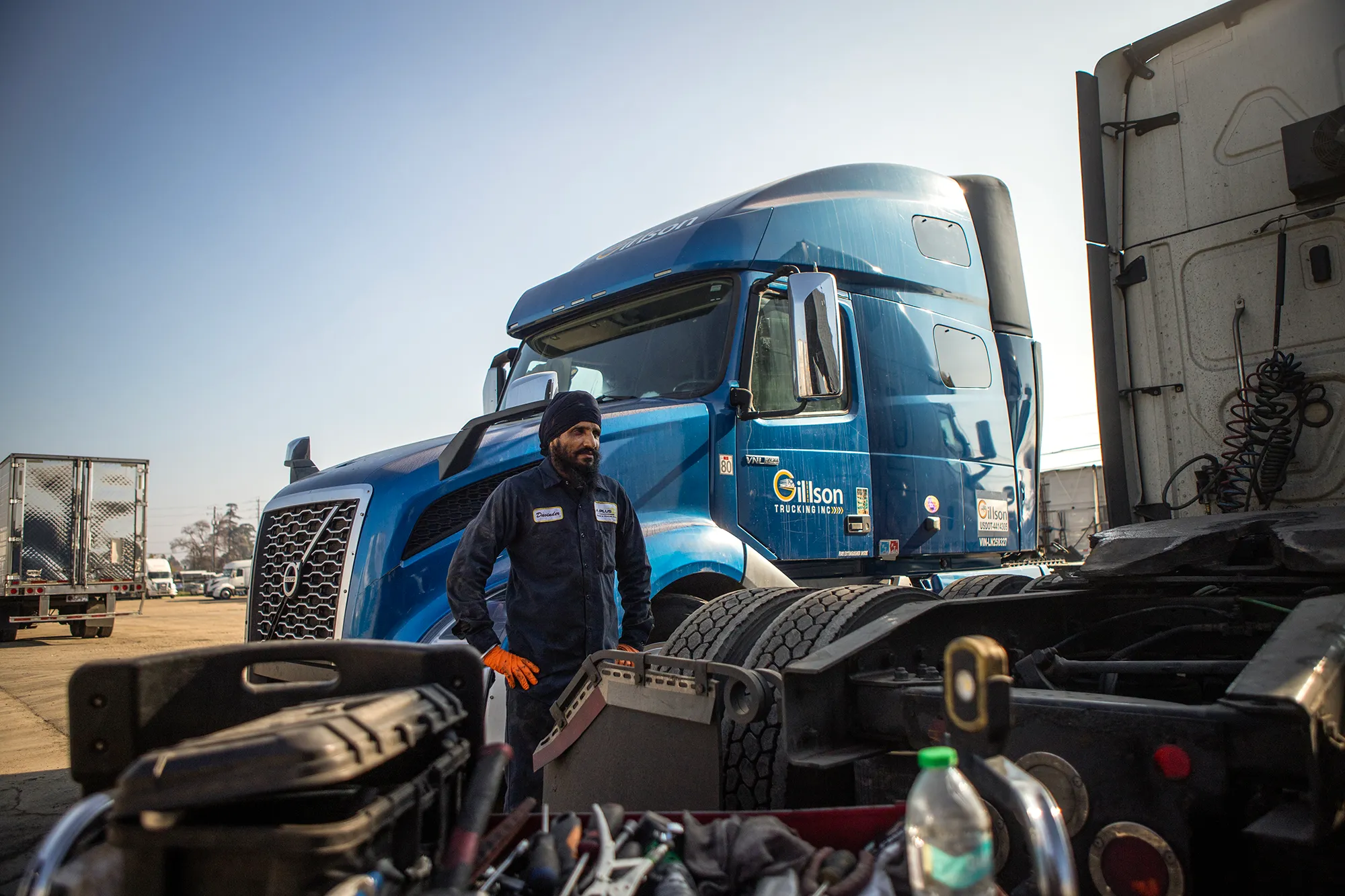 A man stands in front of a blue semi truck