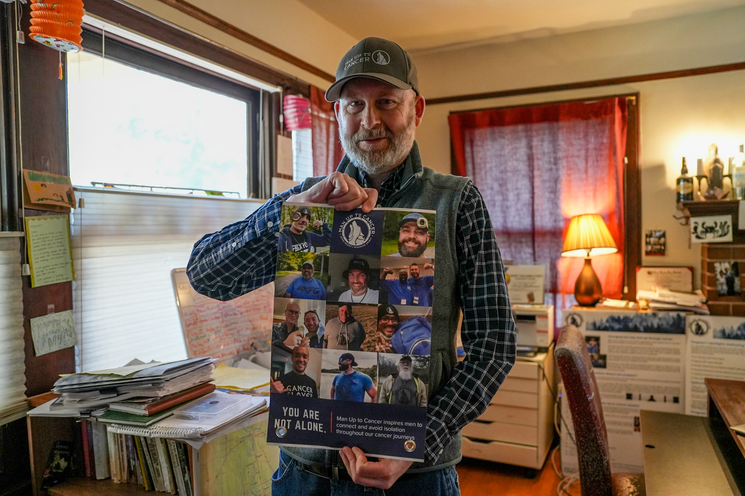 Brad Buchanan, NorCal chapter leader of Man Up to Cancer, holds a sign from the organization in his home. Photo by Denis Akbari.