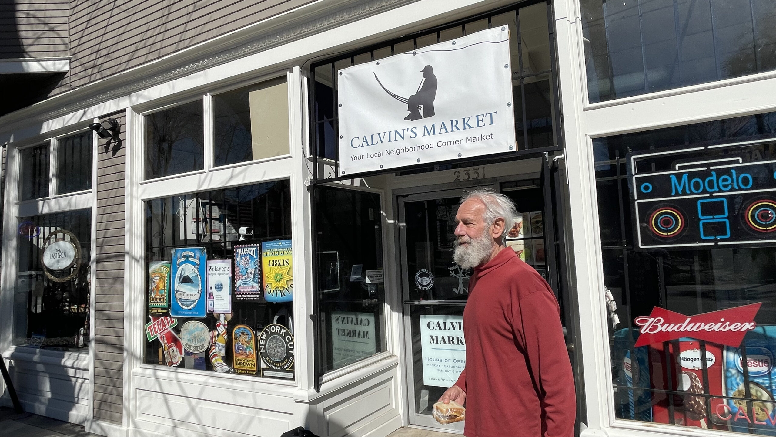 Man standing outside market holding a sandwich