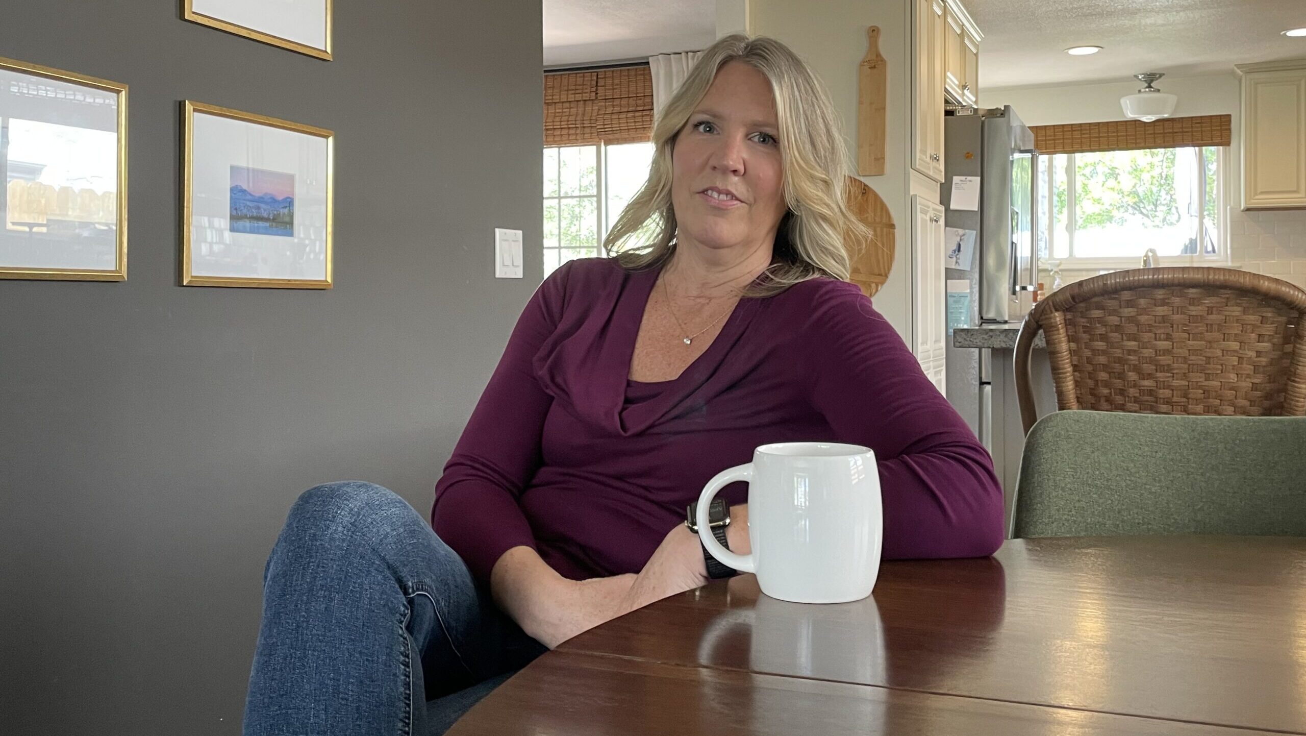 Woman sits at table with a coffee mug.