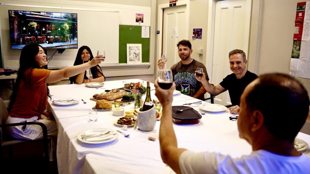 Students sit at a table raising glasses of wine