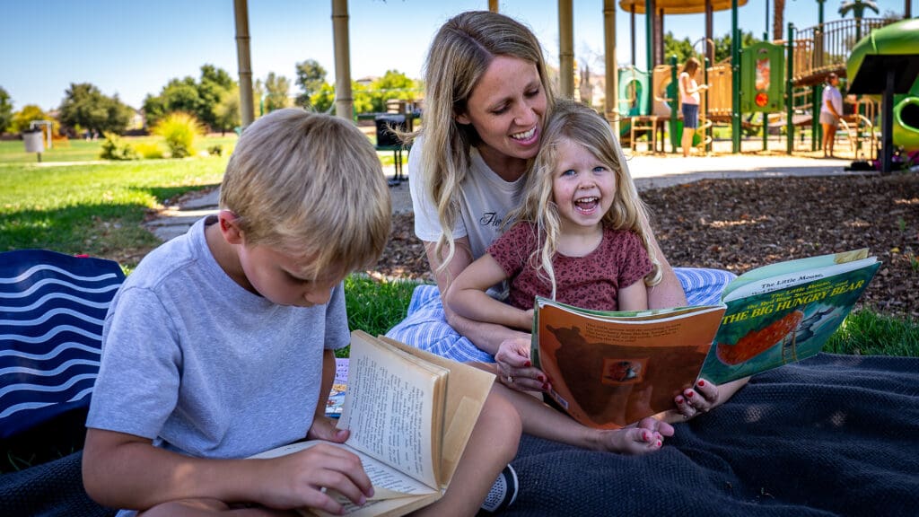 kids and their mom reading in a park
