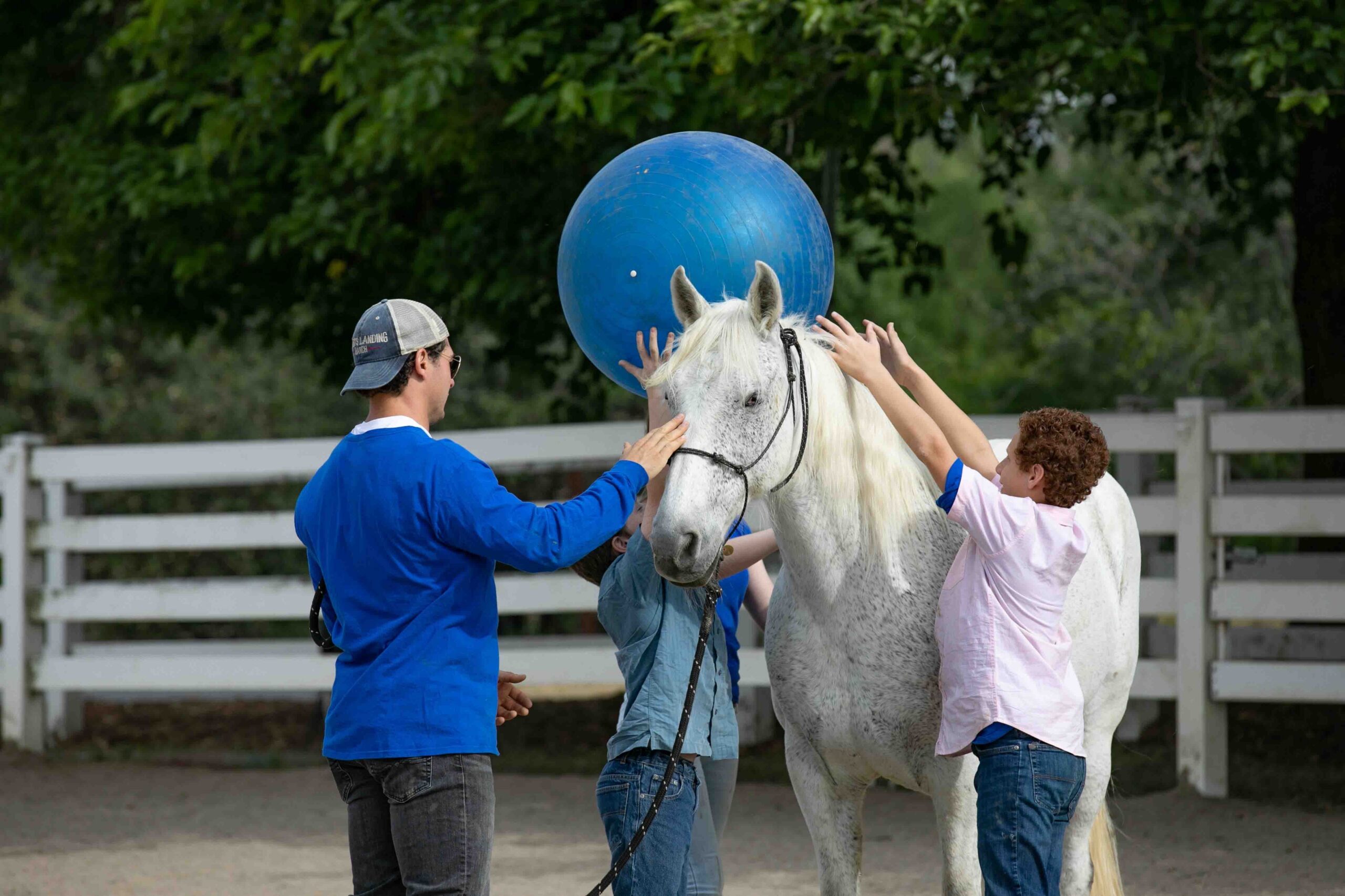 Kids pass a large ball over the top of a horse