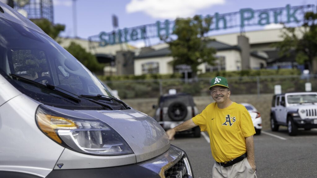 Man in A's fan gear stands outside his RV.